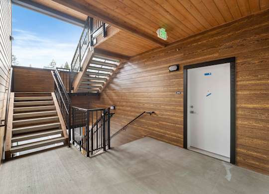 A wooden staircase with a metal railing leads to a door.
