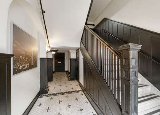 A hallway with a staircase and a painting on the wall.