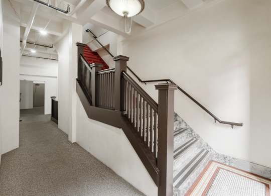 A staircase with a wooden banister and a striped carpet.