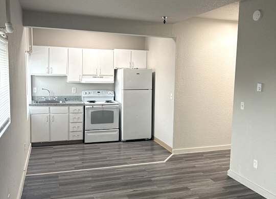 A kitchen with white appliances and cabinets is visible from a hallway.
