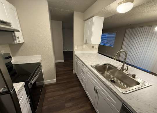 A kitchen with white cabinets and a stainless steel sink.