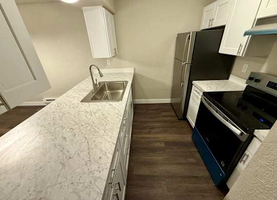 A kitchen with a sink, refrigerator, and oven.