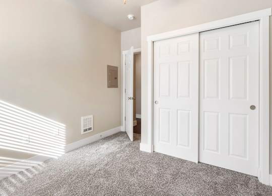 Primary bedroom with closet doors and a carpeted floor.