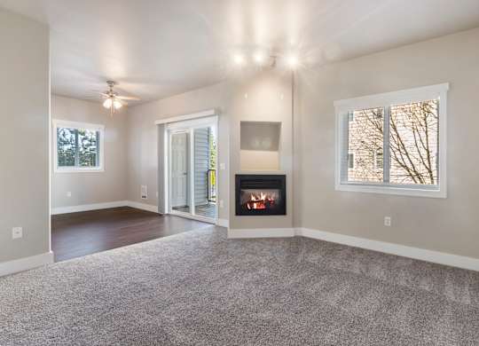 A spacious living room with a fireplace and a ceiling fan.