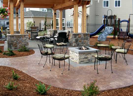 A patio with a firepit and chairs.