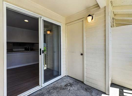 A patio with a sliding glass door and a white door.