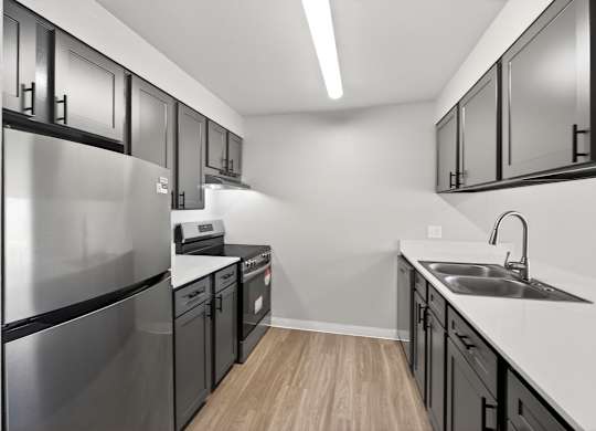 A modern kitchen with stainless steel appliances and black cabinets.