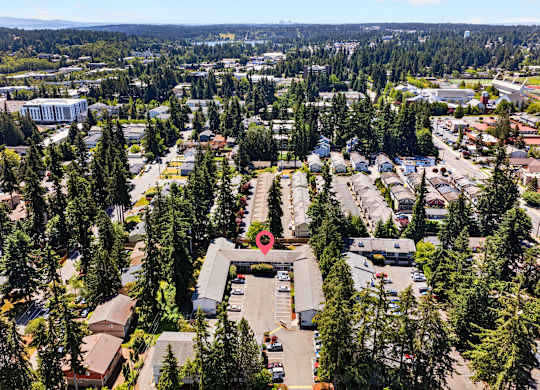 A red pin marks a location in a parking lot in a wooded area.