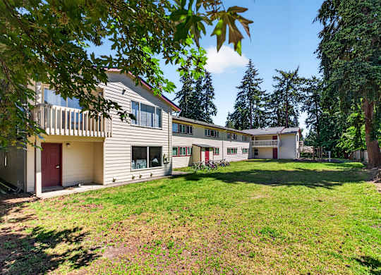 A large, well-maintained lawn in front of a two-story house with a red door.