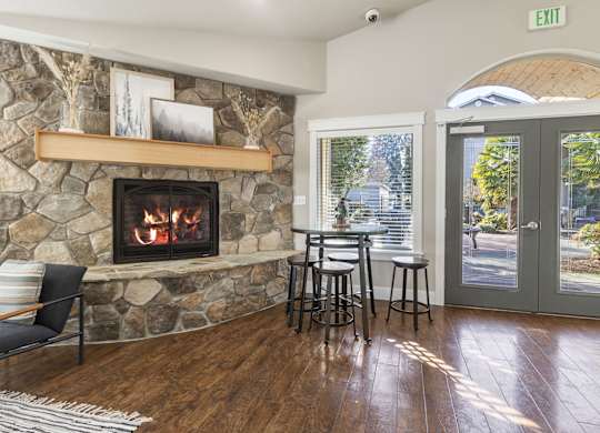 Fireplace with stone surround, tables and charis, and dark wood plank flooring
