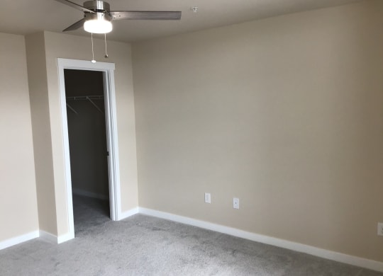 a empty living room with a ceiling fan and a closet