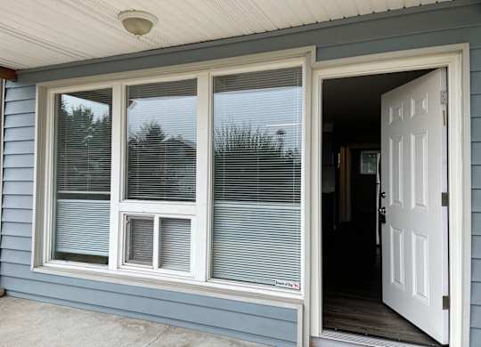 A white door is open to a room with a window.