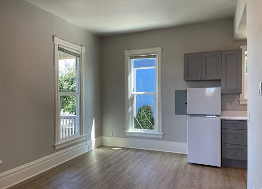 A kitchen with a white refrigerator and wooden floors.