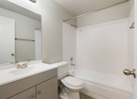 A bathroom with a toilet, sink, and bathtub and shower combo.