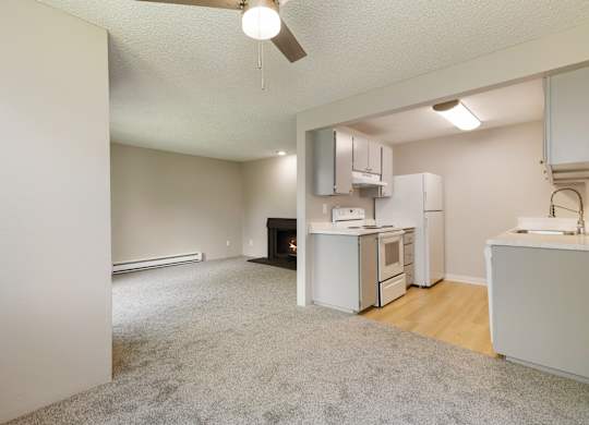 A kitchen area with a white refrigerator, sink, and oven. And grey cabinets.
