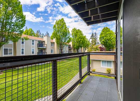 A balcony with a black railing and a view of apartment buildings.