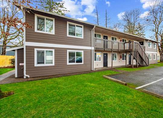 A two-story apartment building with a parking lot in front.