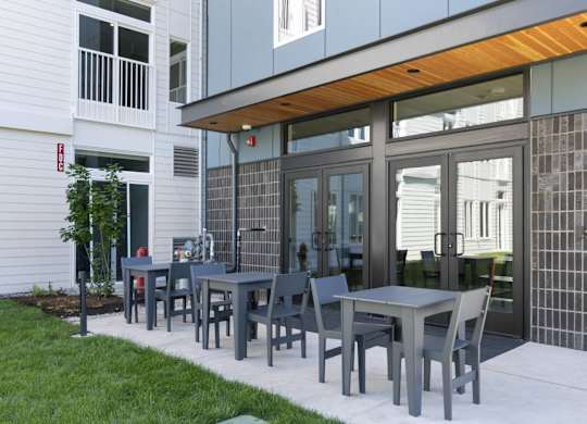 A patio with a table and chairs is in front of a building at The Hub Apartments, Lacey, Washington