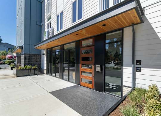 A modern building with a wooden entrance and glass doors at The Hub Apartments, Washington 98503