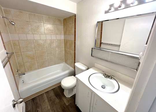A white bathroom with a toilet, sink, and bathtub.