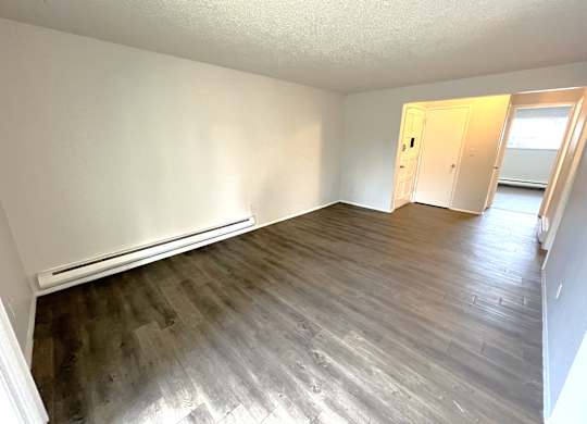 A room with wooden flooring and white walls.