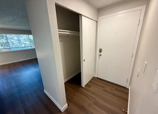 A white door is open to a room with a wooden floor.