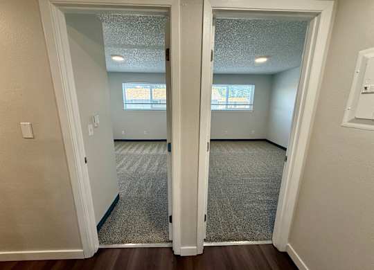 A room with a carpeted floor and a doorway leading to another room.