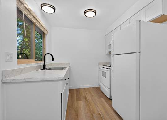 A kitchen with white appliances and a marble countertop.