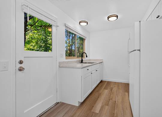 A white kitchen with wood floors and a window.