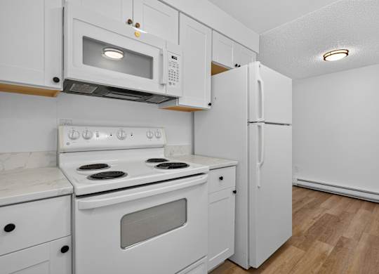 A white kitchen with a stove, microwave, and refrigerator.