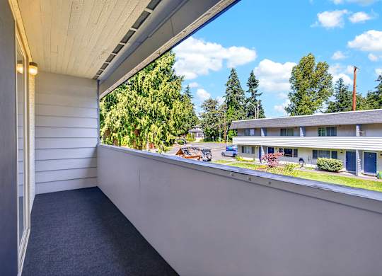 A balcony with a view of a house and trees.