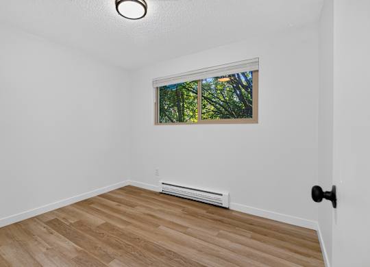 A room with a window and a wooden floor.
