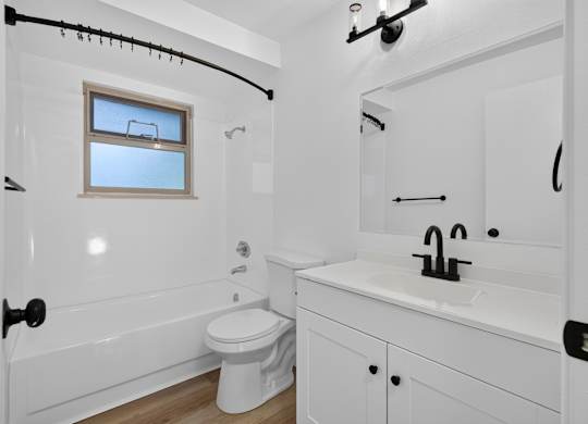A white bathroom with a toilet, sink, and bathtub.
