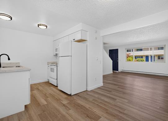 A kitchen with white appliances and wooden floors.