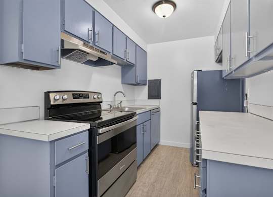 A kitchen with blue cabinets and white countertops.