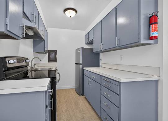 A kitchen with grey cabinets and a white counter.