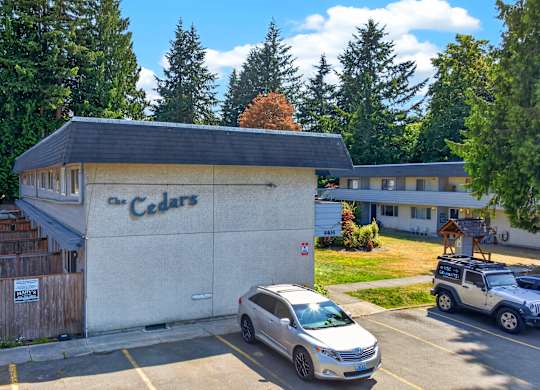 A grey car is parked in front of a building with a sign that says Cedars.