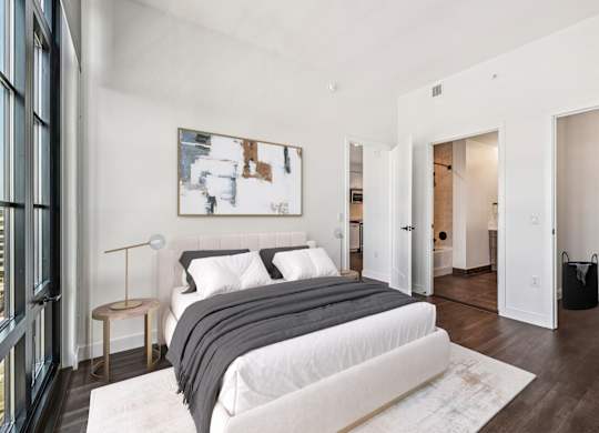 A bedroom with a large bed and a painting on the wall.