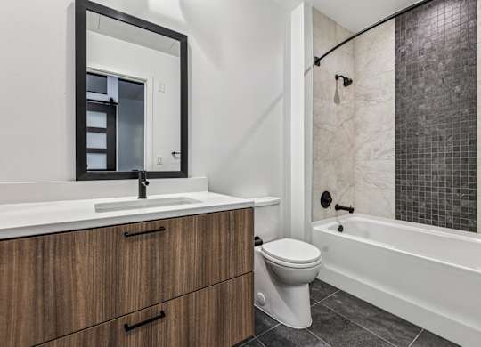 A white sink with a mirror above it and a white toilet next to a bathtub.