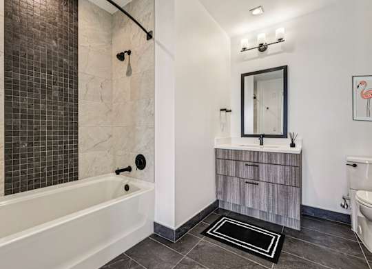 A bathroom with a white tub and a wooden vanity.