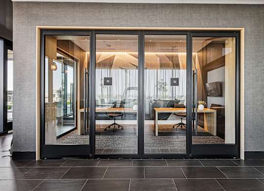A modern office with glass doors leading to a meeting room.