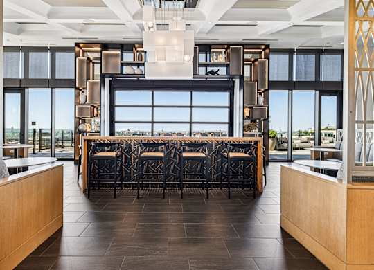A long table with chairs is in the middle of a room with a large window.