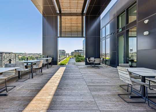 A patio with tables and chairs overlooking a cityscape.