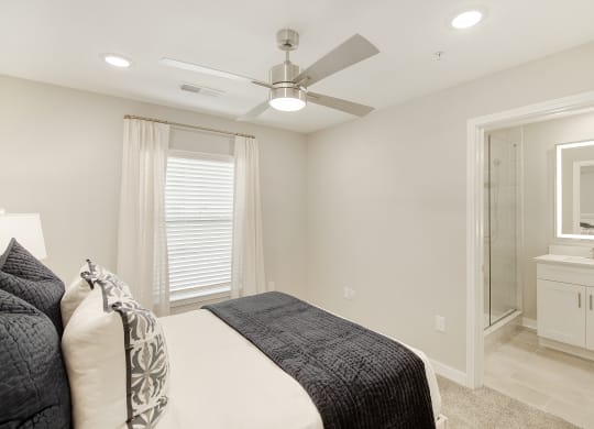 a white bedroom with a large bed and a ceiling fan at The Azul Apartment Homes in Oxford, Mississippi