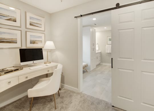 a home office with a computer desk and a door to a bathroom at The Azul Apartment Homes in MS 38655