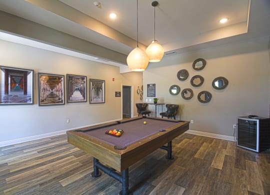 a rec room with a pool table and paintings on the wall at The Met Apartment Homes, Mississippi 39402
