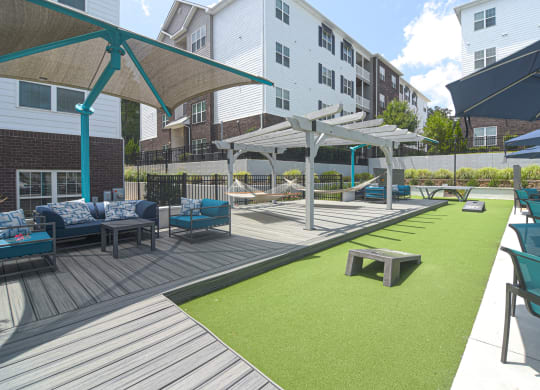 a large patio with chairs and umbrellas and a grassy area with benches at The Met Apartment Homes, Hattiesburg