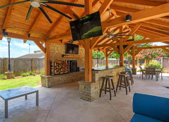 a covered patio with a fireplace and a bar with stools at Summit of Shreveport Apartments, Shreveport, 71105