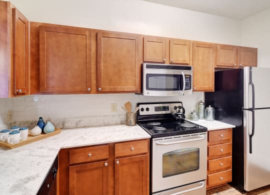 a kitchen with white appliances and wooden cabinets at Summit of Shreveport Apartments, Louisiana