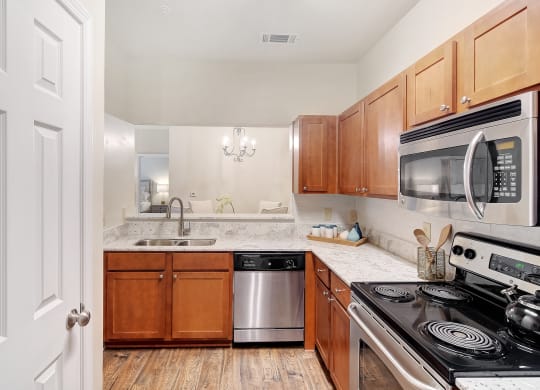 a kitchen with wooden cabinets and stainless steel appliances at Summit of Shreveport Apartments, Shreveport, 71105